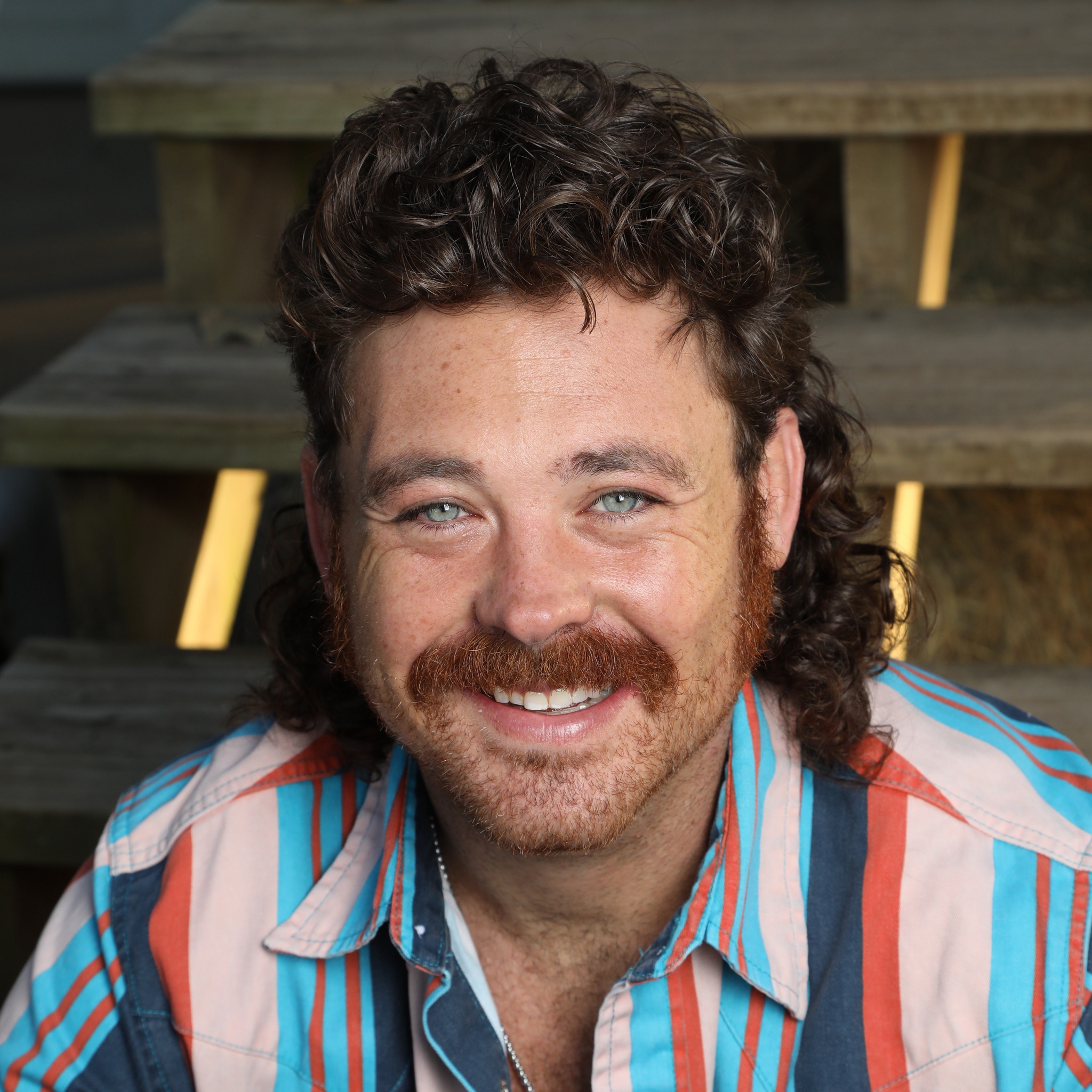 Dean Stanfield smiling on wooden stairs